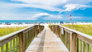 A wooden boardwalk leading to a beach with a flag in the distance. - High Speed Wi-fi, Corner Unit w/Beach and Pool Views (Orange Beach)