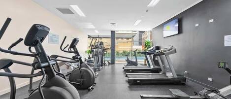 Un gimnasio con cintas de correr, bicicletas estáticas y elípticas.