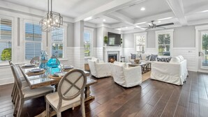 A spacious living room with a fireplace, white furniture, and large windows. - Your Luxury 30A Escape with Private Pool & Coastal Charm (Santa Rosa Beach)