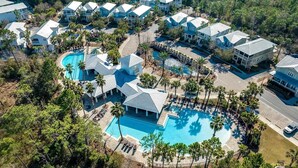 An aerial view of a resort with multiple buildings, a central swimming pool, and surrounding palm trees. - Your Luxury 30A Escape with Private Pool & Coastal Charm (Santa Rosa Beach)
