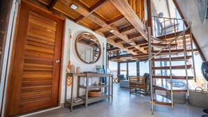 Un intérieur en bois avec un escalier en colimaçon, un miroir rond et une enseigne indiquant « MAISON AUX TORTUES ».