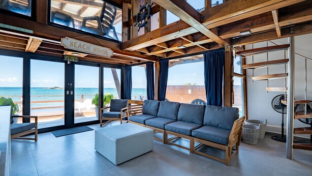 Un vaste espace de vie comprenant un grand canapé, une table basse et une vue sur la plage.