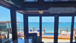 Une maison de plage avec vue sur l’océan, une piscine et un espace détente avec des fauteuils.