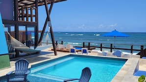 Un espace piscine comprenant deux fauteuils Adirondack, un hamac et une vue sur l’océan.