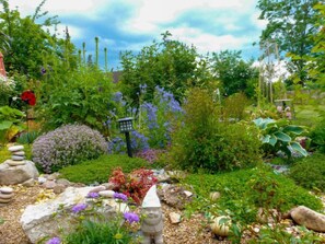A garden with a variety of plants, a stone lantern, and a gnome statue. - Schmetterlingsgarten by Interhome (Hüfingen)