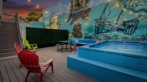 Une terrasse ornée d’une fresque représentant une tortue de mer et des bateaux, avec un jacuzzi et des sièges d’extérieur.