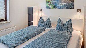 A bedroom with a bed, a window, a wall-mounted picture, and a radiator. - Franzi 3 by Interhome (Arrach)