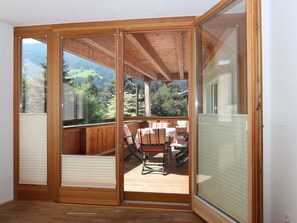 Una habitación con puerta corrediza de vidrio que da a una terraza exterior con mesa y sillas.