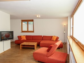 Una sala de estar con un sofá modular, una mesa de centro de madera y un televisor.