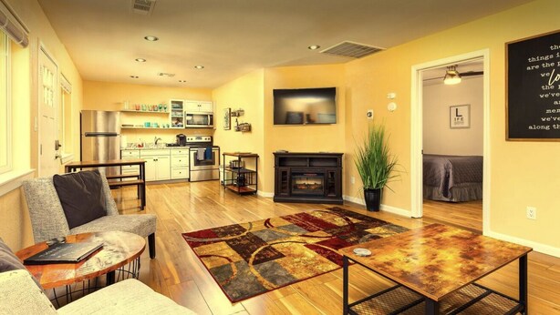 A modern living room with a fireplace, a dining area, and a kitchen in the background. - Newly remodeled quaint Cottage (Three Rivers)