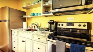 A compact kitchen with a refrigerator, microwave, stove, and coffee maker. - Newly remodeled quaint Cottage (Three Rivers)
