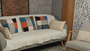 Un sofá con cojines estampados, una mesa de centro de vidrio y un suelo con diseño.