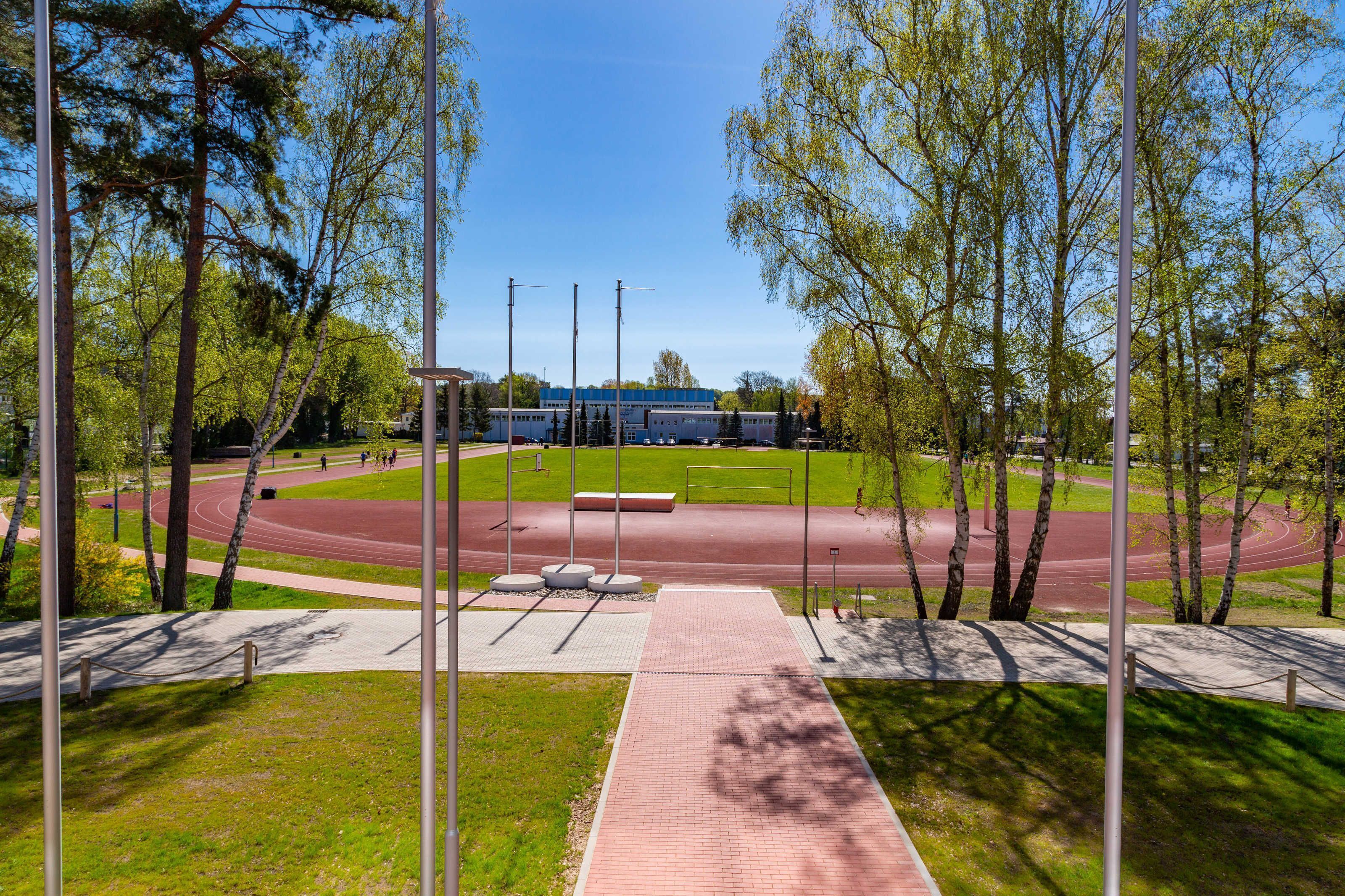 Un parco con una pista di atletica, alberi e un edificio sullo sfondo.
