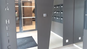 Eine moderne Hotellobby mit Glastür, einer Rezeption und einem an der Wand befestigten Gepäckfach.
