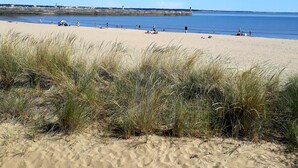 Ein sandiger Strand mit blauem Himmel und einer fernen Küstenlinie.