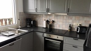 A modern kitchen with grey cabinets, a black countertop, a coffee maker, a toaster, and a wine bottle. - Apartment No. 2 in the Main House – bright, cozy, and well equipped (Havixbeck)
