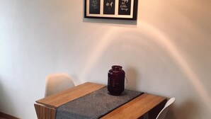 A dining area with a wooden table, two chairs, a patterned table runner, a decorative jar, and a wall-mounted light fixture. - Apartment No. 2 in the Main House – bright, cozy, and well equipped (Havixbeck)