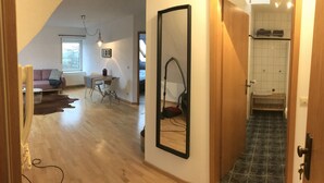 A hallway leading to a living area with a sofa, a table, and a mirror. - Apartment No. 2 in the Main House – bright, cozy, and well equipped (Havixbeck)