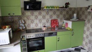 A kitchen with green cabinets, a microwave, a stove, and a sink.
