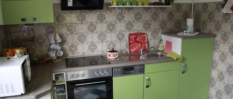 A kitchen with green cabinets, a microwave, a stove, and a sink.