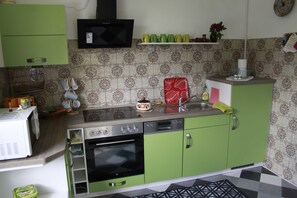 A kitchen with green cabinets, a microwave, a stove, and a sink.