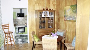 Un coin repas comprenant un buffet en bois, des chaises en osier et une table agrémentée d’un vase et de verres.
