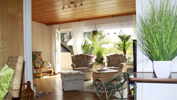 A cozy living room with wicker furniture, a wooden ceiling, and a view of the outdoors.