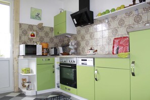 A kitchen with green cabinets, a microwave, a coffee maker, and a stove.