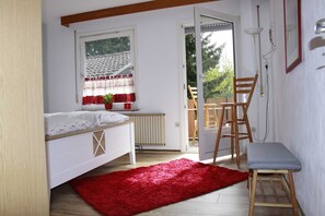 Een slaapkamer met een bed, een rood vloerkleed, een houten stoel en een klein krukje.