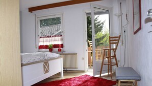 A bedroom with a bed, a red rug, a wooden chair, and a small stool.