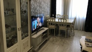 A living room with a television, dining table, and chairs. - 4 rooms apartment  (Batumi)