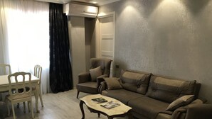 A living room with a sofa, armchair, coffee table, and dining table. - 4 rooms apartment  (Batumi)