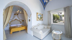 A bedroom with a bed, a sofa, a small table, and a window with curtains.