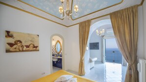 A hotel room with a bed, a painting, a bathroom, and a view of the outside.