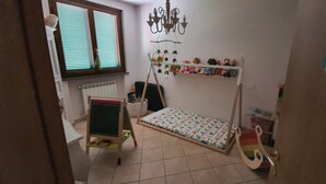 A child's bedroom with a bunk bed, a small desk, a rocking chair, and a hanging mobile.