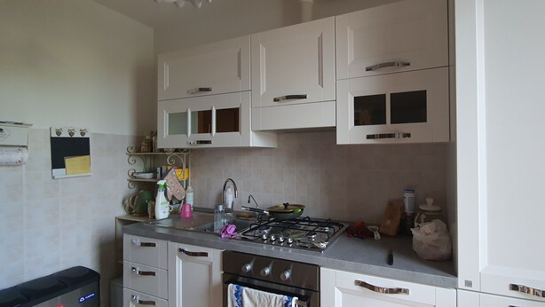 A kitchen with white cabinets, a gas stove, and a sink.