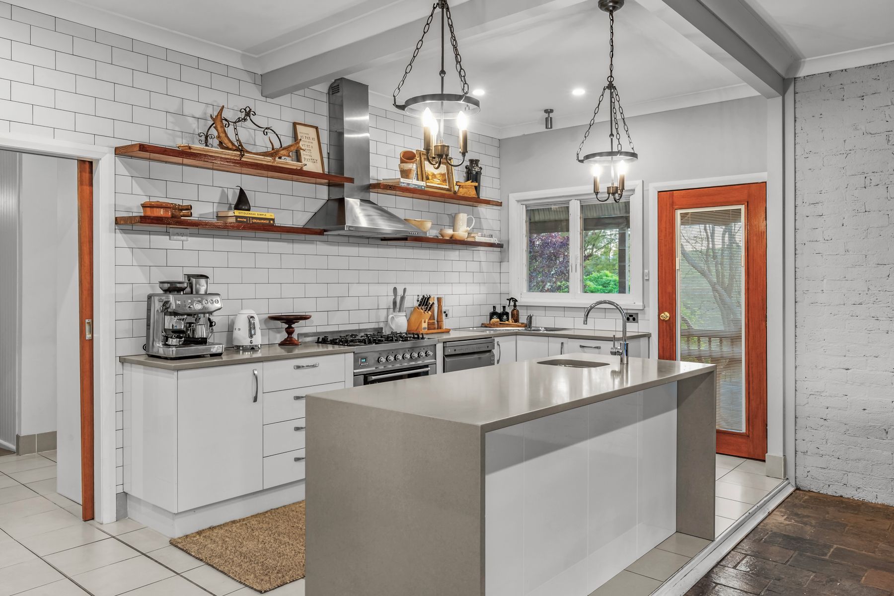 A modern kitchen with white cabinetry, a central island, and pendant lighting.