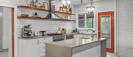 A modern kitchen with white cabinetry, a central island, and pendant lighting.