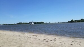 A sandy beach with a sailboat in the distance.