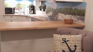 Una cocina moderna con encimera de madera, una lámpara de araña y vistas al exterior a través de un ventanal.
