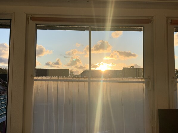 A window with a view of the sky and clouds, with sunlight streaming through.