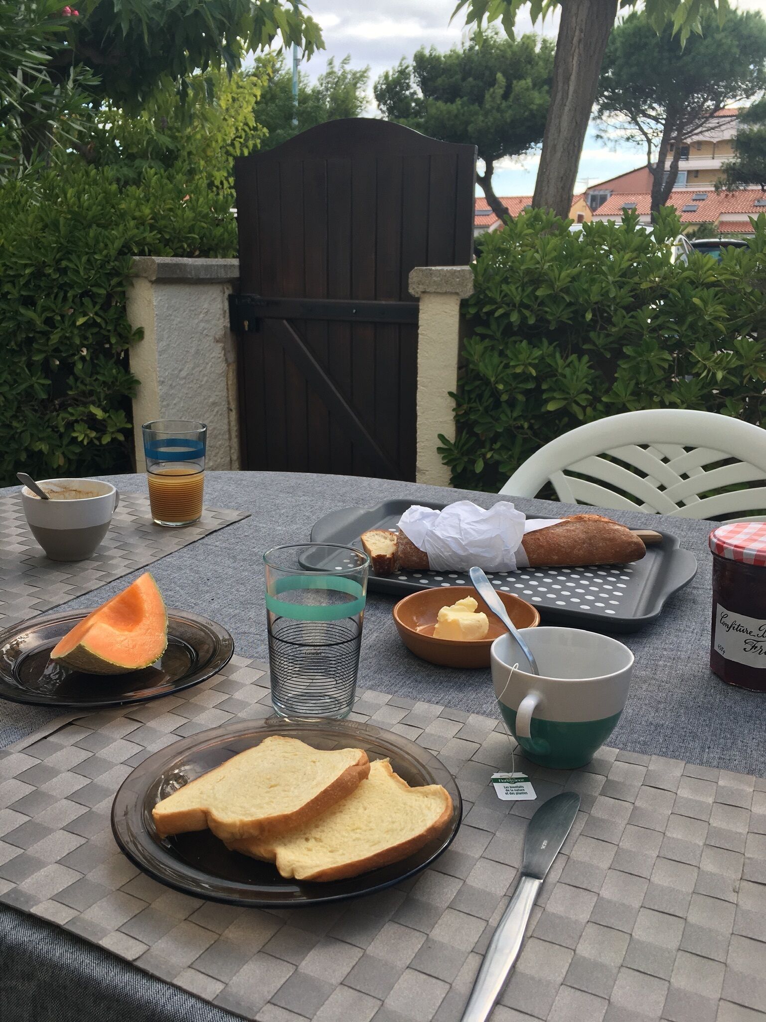 Taula a l'aire lliure preparada amb menjar i begudes, incloent pa, mantega, melmelada i un got d'aigua.
