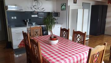 A compact kitchen with modern appliances, a dining area with a checkered tablecloth, and a potted plant.