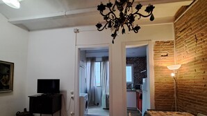 A living room with a TV, a washing machine, and a dining area with a table and chairs. - Casa Mia Barcelona & Barça (Hospitalet de Llobregat)