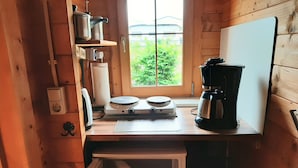 Een compact keuken met houten wanden, een raam met uitzicht, een koffiezetapparaat en een klein aanrecht.