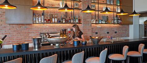 A bar area with a brick wall, hanging pendant lights, and bar stools.