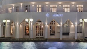 Un hotel de varios pisos con una piscina al frente.