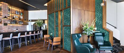 A bar area with wooden bar counters, multiple bar stools, and a green patterned wall.