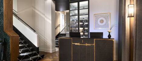 A modern reception area with a staircase, a wine rack, and a decorative wall piece.