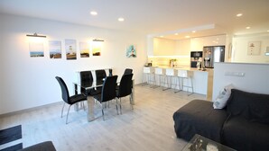 Ein modernes Wohnzimmer mit Essbereich, Küche und einer Couch.